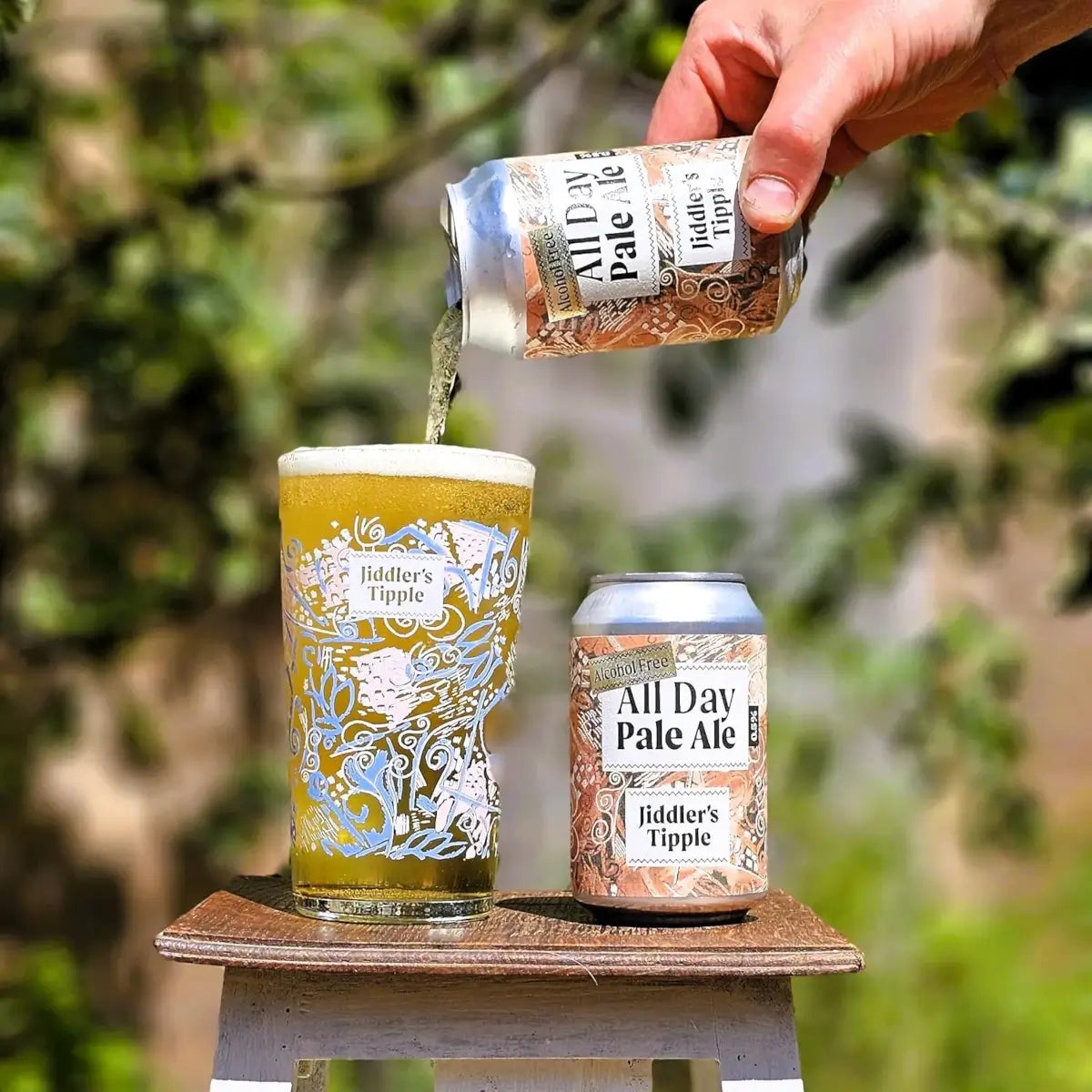 Person pouring Jiddler's Tipple All Day Pale Ale into a glass with outdoor background